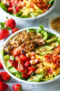 two white bowls filled with salad and strawberries