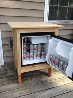 an open mini fridge with soda cans in it