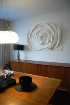 a wooden table topped with a bowl of food next to a painting on the wall