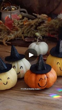 four pumpkins with faces painted on them sitting in front of a pile of other pumpkins