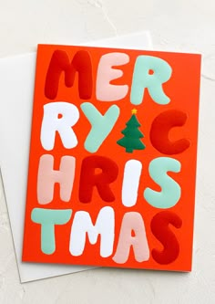 a card with the words merry christmas written in green, red and white on it