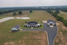 an aerial view of a large house in the middle of a field with water and trees