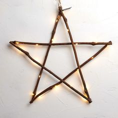 a lighted star hanging on the wall with lights around it's sides and branches in the shape of a pentagram