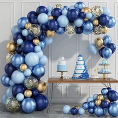 a blue and gold birthday party with balloons, cake and desserts on the table