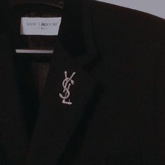 a black shirt with a small white logo on the chest and an embroidered saint laurent t - shirt