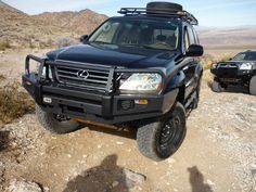 two vehicles parked on the side of a dirt road