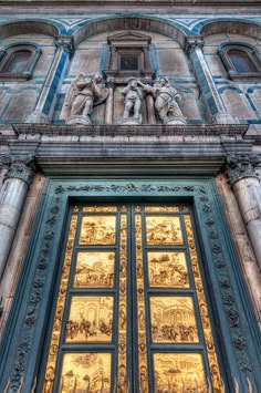 an ornate building with many windows and statues on the front door is lit up at night