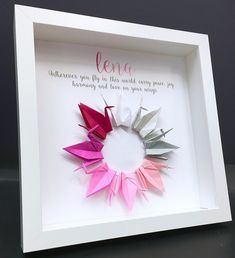 an origami wreath with the words len written on it in pink, white and grey