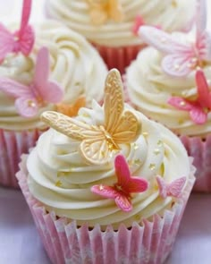 cupcakes with white frosting and pink butterflies on the top one is decorated