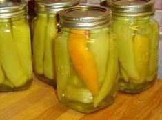 several jars filled with pickles on top of a wooden table