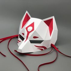 an origami cat mask with red ribbon tied around it