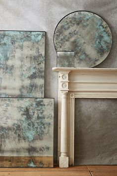 a white fireplace with blue and green paint on it's mantle next to a mirror