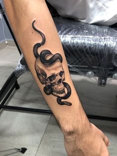 a man's arm with a snake and skull tattoo on the left inner forearm