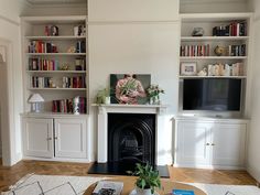 a living room with bookshelves and a fireplace in the center, surrounded by white cabinets