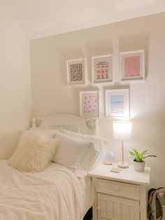 a white bed with pillows and pictures on the wall