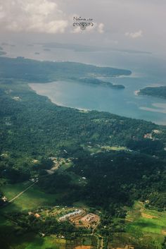 the view from an airplane looking down on some green land and blue water in the distance