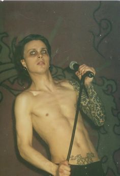 a shirtless man holding a microphone in his right hand