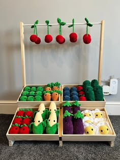 an assortment of crocheted fruits and vegetables displayed in wooden trays on carpeted floor