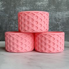 four pink vases stacked on top of each other in front of a gray wall