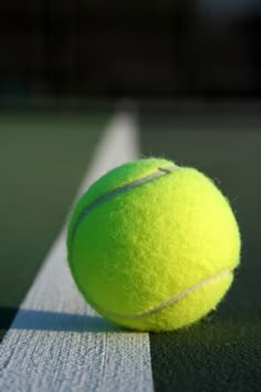 a tennis ball sitting on the edge of a court with white lines in front of it