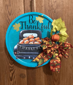 a blue plate that says be grateful with pumpkins on it and a bow hanging from the front