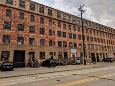 an old brick building on the corner of a street with cars parked in front of it