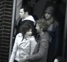 two women and a man standing in front of a building