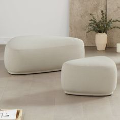 two white couches sitting next to each other on the floor in front of a mirror