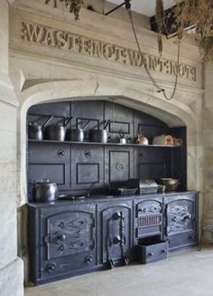 an old fashioned stove with pots and pans on it's shelves in a kitchen