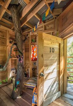 the inside of a tree house with wooden floors and walls, decorated with colorful flags