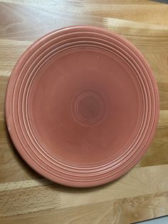 a pink plate sitting on top of a wooden table