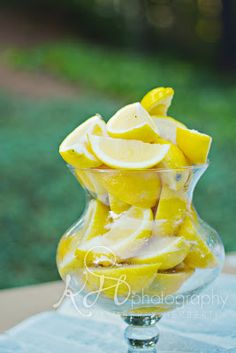 a glass vase filled with sliced lemons on top of a blue cloth covered table