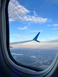 an airplane wing is seen through the window as it flies in the blue sky with white clouds