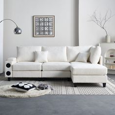 a white couch sitting on top of a rug in a living room next to a lamp