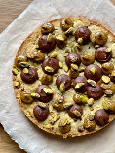 a pizza topped with nuts and pistachios on top of parchmented paper