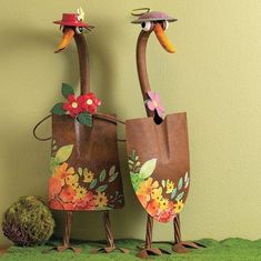 two metal birds with hats and flowers on their heads are standing next to each other