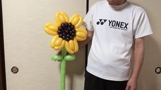 a man standing next to a flower shaped balloon in the shape of a sunflower