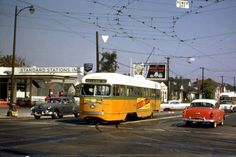 an orange and white bus driving down a street next to other cars on the road