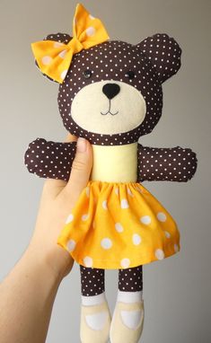 a hand holding a teddy bear with polka dots on it's dress and shoes