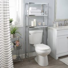 a white toilet sitting next to a sink in a bathroom near a window with curtains