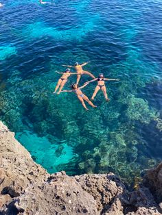 three people are floating in the clear blue water on their back legs and arms above them