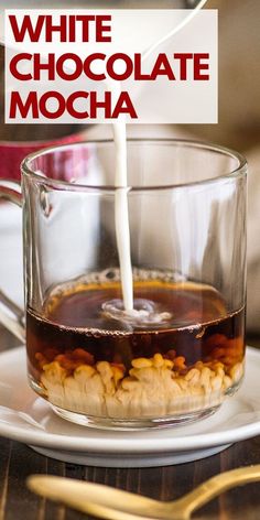 a glass cup filled with chocolate mocha sitting on top of a white saucer