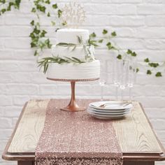 a wedding cake sitting on top of a wooden table next to plates and wine glasses