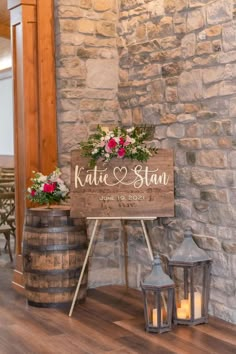 a wooden sign sitting on top of a table next to two vases filled with flowers