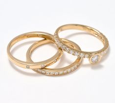 three gold wedding rings with diamonds on them