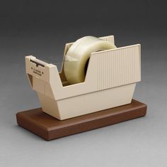 a white tape dispenser sitting on top of a wooden stand