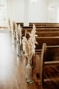 flowers in vases sitting on the pews of a church with empty pews