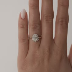 a woman's hand with a diamond ring on top of her finger and the other hand holding an engagement ring