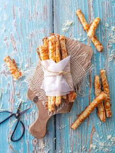 french fries wrapped in wax paper on a cutting board next to some scissors and twine