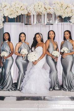 a group of women standing next to each other in front of a white flower arrangement